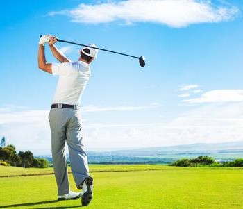 32094547-man-playing-golf-on-beautiful-sunny-green-golf-course-hitting-golf-ball-down-the-fairway-from-the-te.jpg
